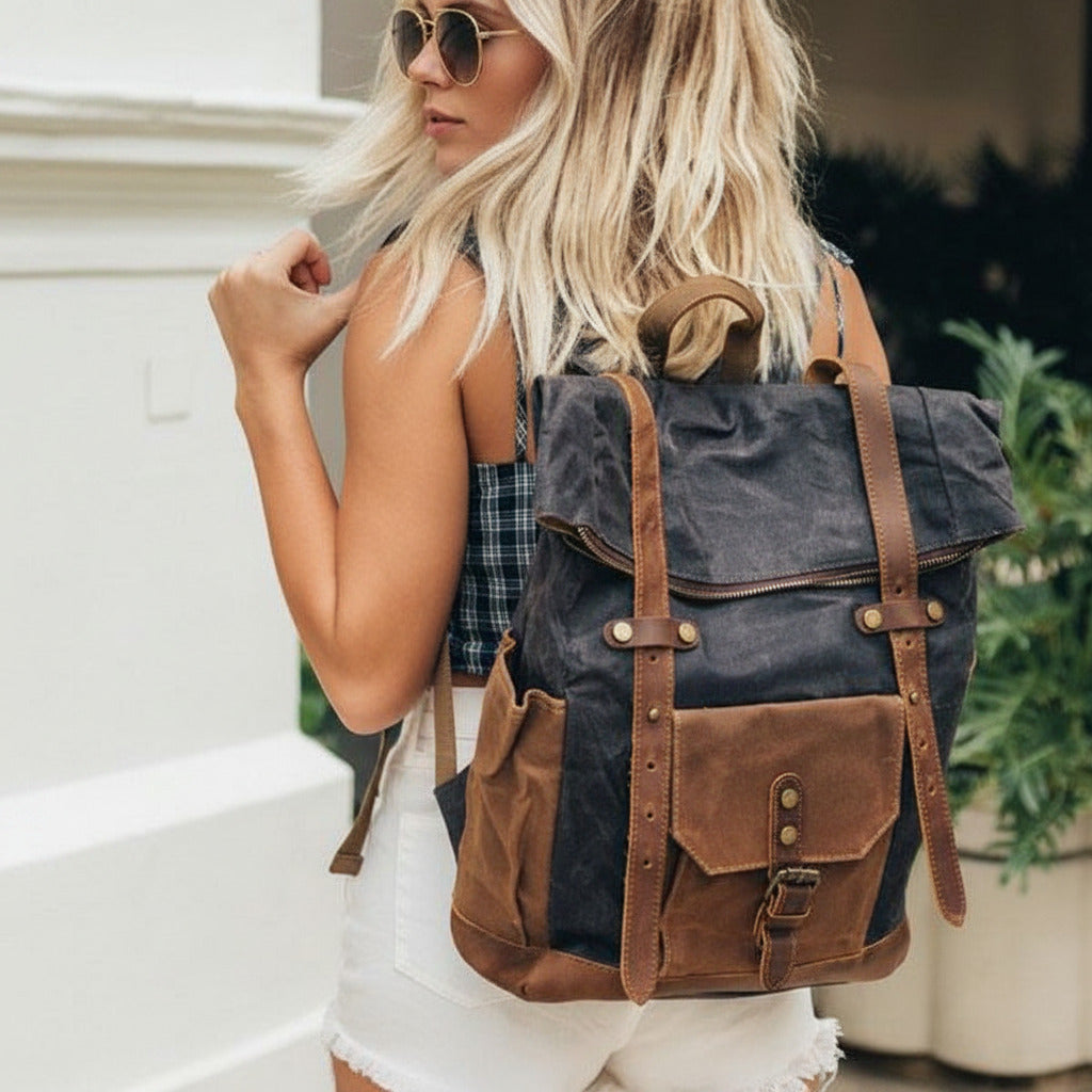 Eine modebewusste Frau geht mit dem dunkelgrauen Vintage Rucksack aus gewachstem Canvas durch ein urbanes Viertel, moderner Casual-Look im herbstlichen Licht