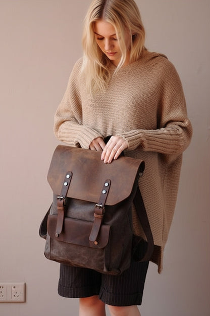 braunem Canvas-Rucksack mit Lederklappe und Schnallen von VINTAGE TAR, getragen vom Model in einem beigen Pullover, Vorderansicht