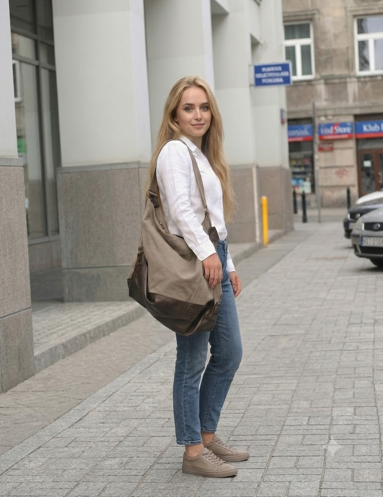 Beigefarbene Hobo-Umhängetasche aus Canvas mit braunen Kunstlederbesätzen von SAFFI, getragen von einem Model auf einem Bürgersteig in der Stadt, Seitenansicht, lässiger LookBeige canvas hobo shoulder bag with brown faux leather trim by SAFFI, worn by model on city sidewalk, side view, casual styling