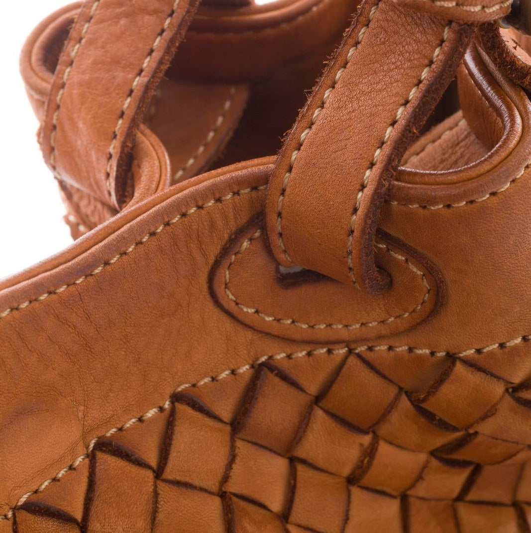 Nahaufnahme der handgeflochtenen Lederstruktur der cognacbraunen Cestino Tasche, exquisite handwerkliche Verarbeitung