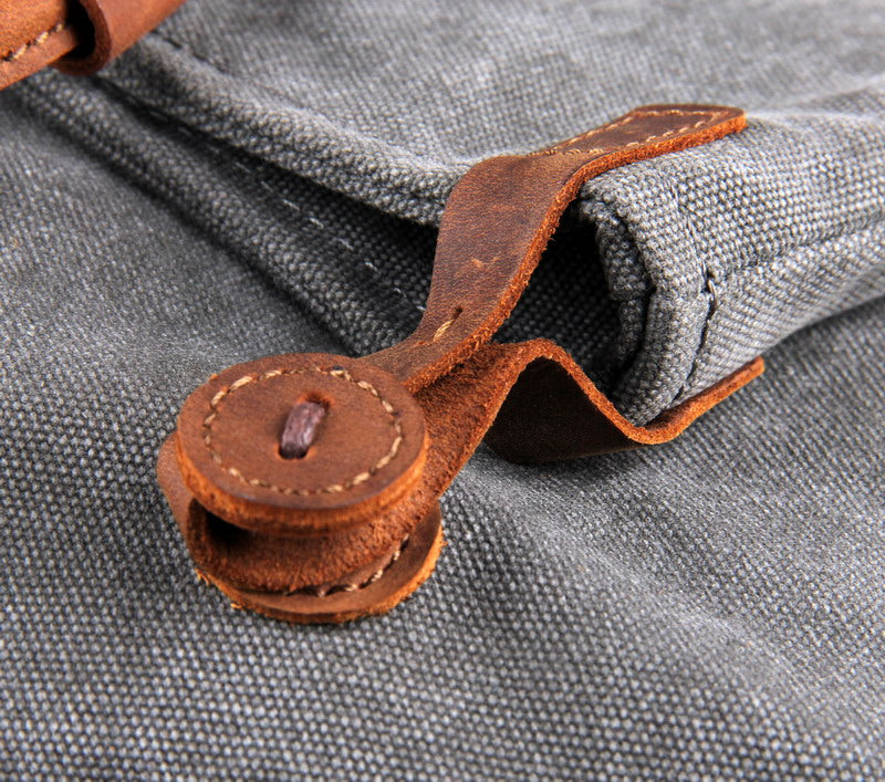 Nahaufnahme der hochwertigen Details aus echtem Kalbsleder und der präzisen Nähte an der grauen Canvas-Tasche.