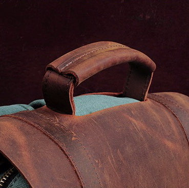 Vintage Rucksack aus schwerem Canvas und braunem Echtleder in der Seitenansicht, ergonomisch gepolsterte Schultergurte und stabiler Tragegriff für optimalen Komfort.