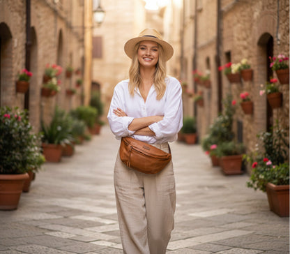 Close-up Moodbild: Stilvolles Damen-Outfit mit weißem Hemd und großer cognac brauner Gürteltasche aus Leder in den charmanten Straßen Italiens
