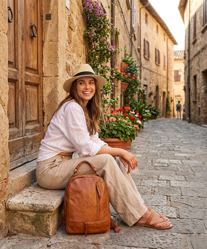 Eine junge Frau läuft durch eine charmante Altstadtstraße, auf dem Rücken der stilvolle Vintage Lederrucksack SICILLA in Cognac-Braun, passend zu einem urbanen Frühlings-Outfit.